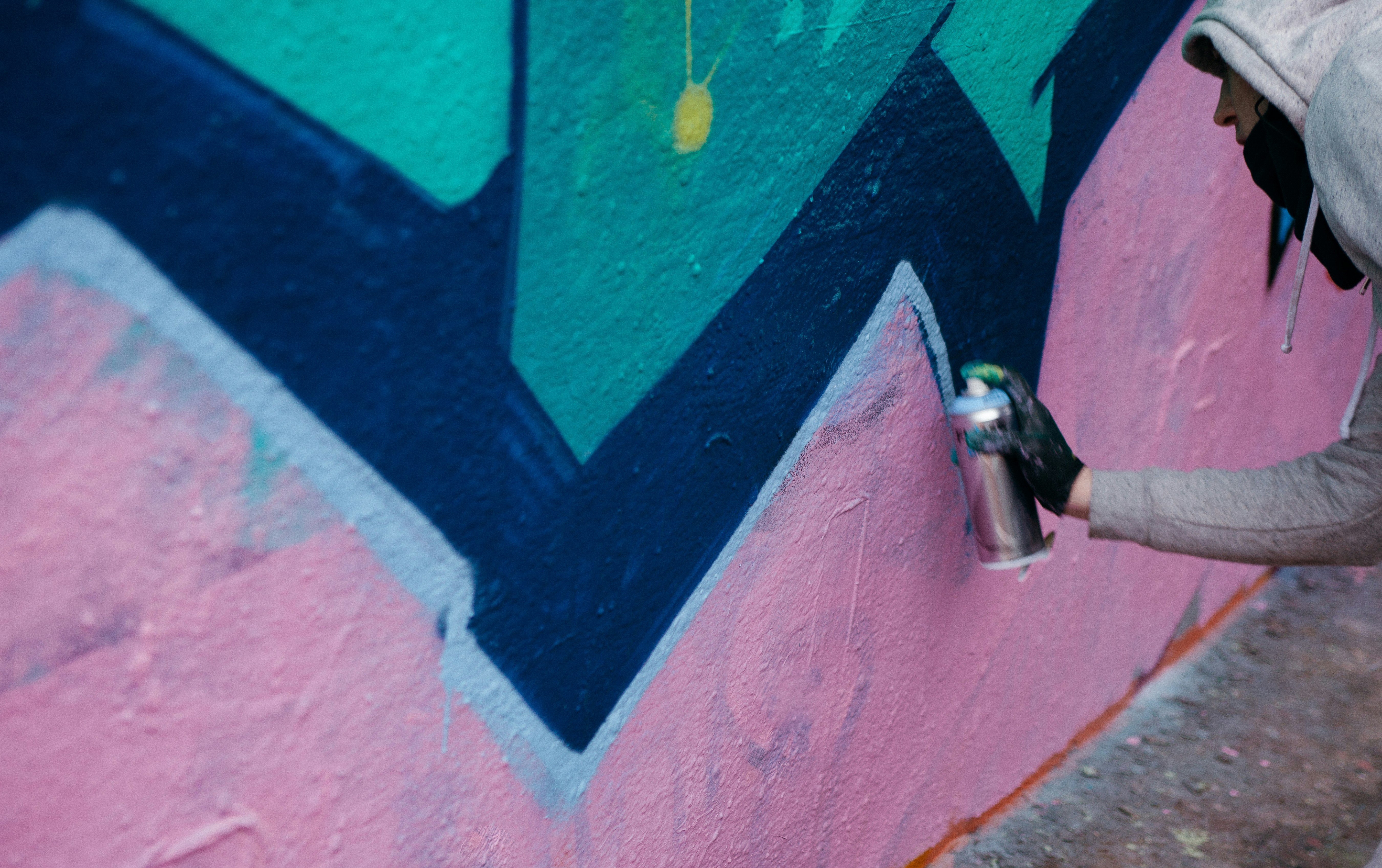 person in hoodie making a graffiti art